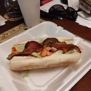 a hot dog with bacon and lettuce