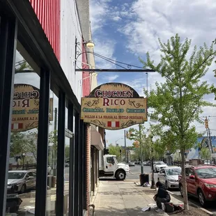 a woman sitting on the sidewalk in front of a restaurant