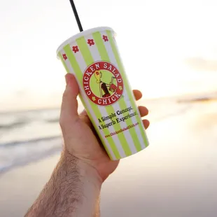 a hand holding a cup of chicken salad