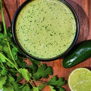 a bowl of cilantro sauce with a lime slice and cilantro