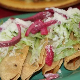 a plate of tacos with lettuce and onions