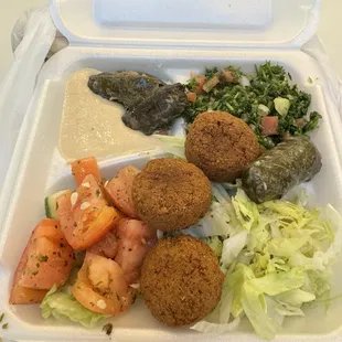 This is a build your own bowl with a salad as base tabuleh and hummus served  with Falafel and an extra side of grape leaves rolls