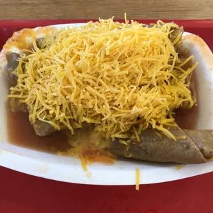 Order of 6 rolled beef tacos in red sauce with shredded cheddar on top.