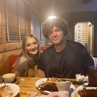 a man and a woman sitting at a table with food