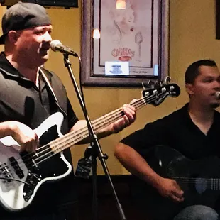 a man playing guitar and singing into a microphone