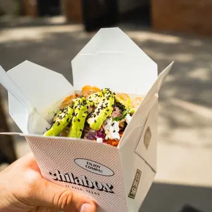 a hand holding a box of food