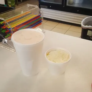 a cup of ice cream next to a container of shredded cheese