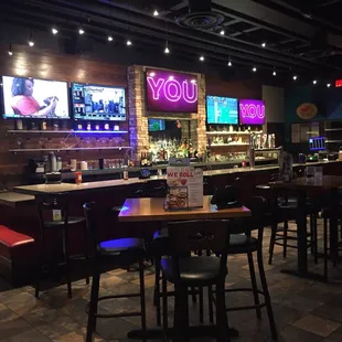 a bar with neon signs and bar stools