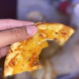 a hand holding a piece of pizza