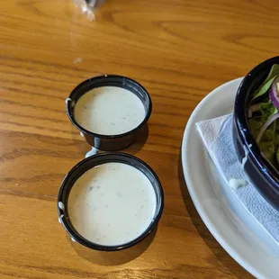 a bowl of salad and two small bowls of dressing