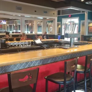 a restaurant with a long bar with red seats