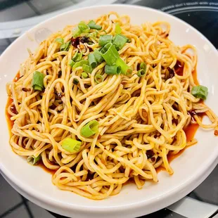 a plate of spaghetti with green onions