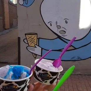 a hand holding two cups of ice cream