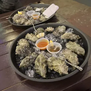 two platters of oysters with dipping sauce