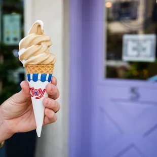 a hand holding a cone of ice cream