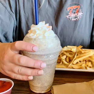 a person holding a cup of ice cream and french fries