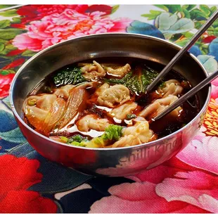 a bowl of soup with chopsticks