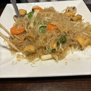 a plate of noodles with chopsticks