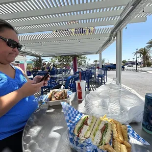 a woman sitting at a table with a sandwich and fries
