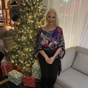 a woman standing in front of a christmas tree