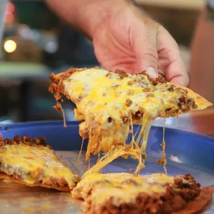 a person taking a slice of pizza