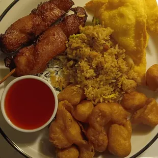 a plate of chinese food and a cup of sauce
