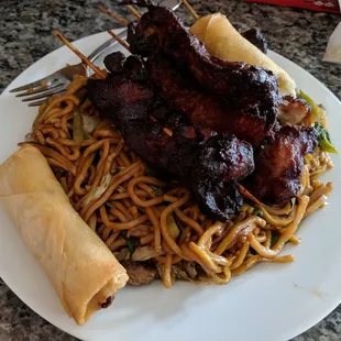 Teriyaki chicken on a stick, vegetable lomein, spring rolls