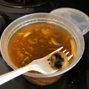 a plastic bowl of soup with a spoon in it
