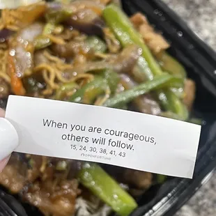 a hand holding a piece of paper that says when you are courageous others will follow