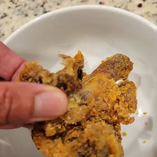 a hand holding a fried chicken