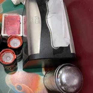 The dirty/sticky napkin dispenser and sugar bottle.