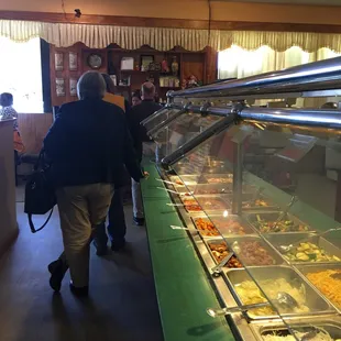 a group of people walking through a buffet