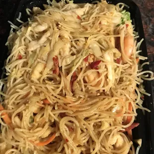a plate of noodles with shrimp and vegetables