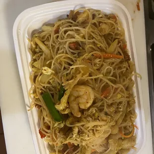 a plate of noodles with shrimp and vegetables