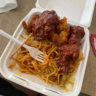 a take out container with noodles and meat