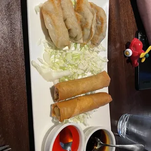 a plate of chinese food with dipping sauces
