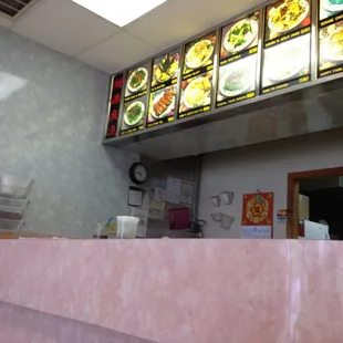 a restaurant counter with a menu in the background