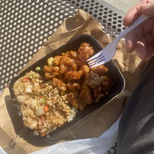 a hand holding a fork over a tray of food