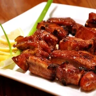 a plate of grilled meat with lemon wedges