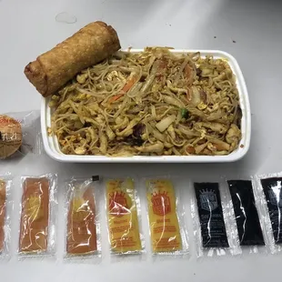 a plate of noodles, a roll, and a bag of noodles