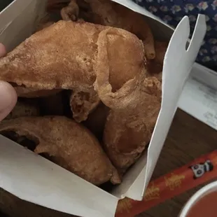 a person holding a box of fried food
