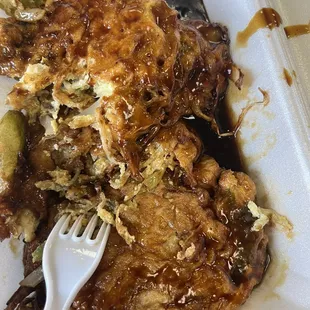 Egg foo young in a soup of soy sauce.