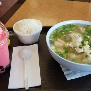 a bowl of soup and a drink on a tray