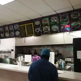 a man standing at the counter of a restaurant