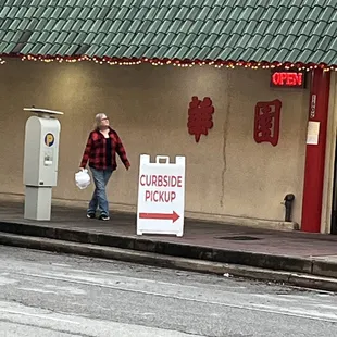 a woman walking past a curbside pick up sign