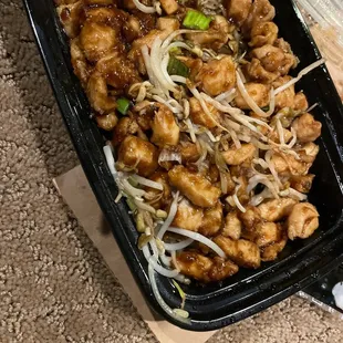 a black plastic container of chicken and vegetables