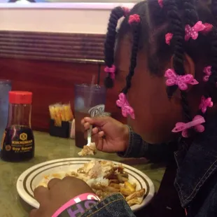 a little girl eating a plate of food