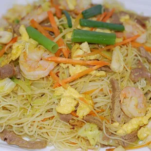 a plate of noodles with shrimp and vegetables