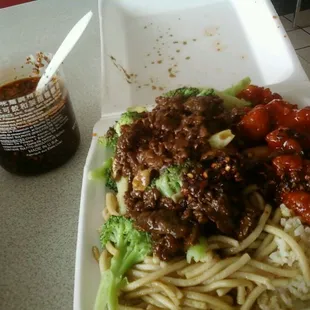 a takeout container with noodles, beef and broccoli