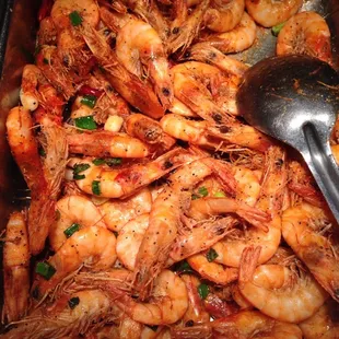 a tray of cooked shrimp with a spoon